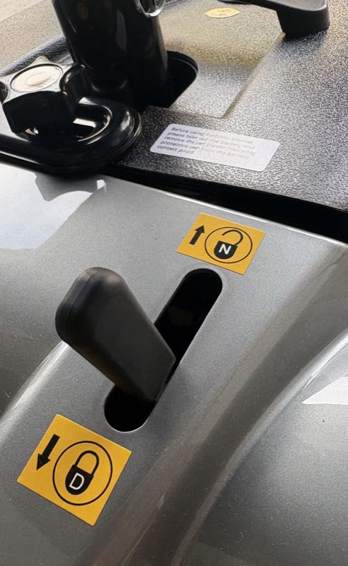 The black free-wheel lever on the rear body, between two yellow decals: N with an open padlock above it, D with a closed padlock below it
